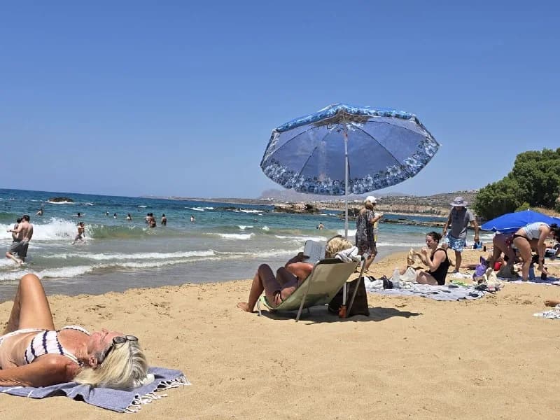 Travelers relaxing beneath umbrellas on a sunny beach