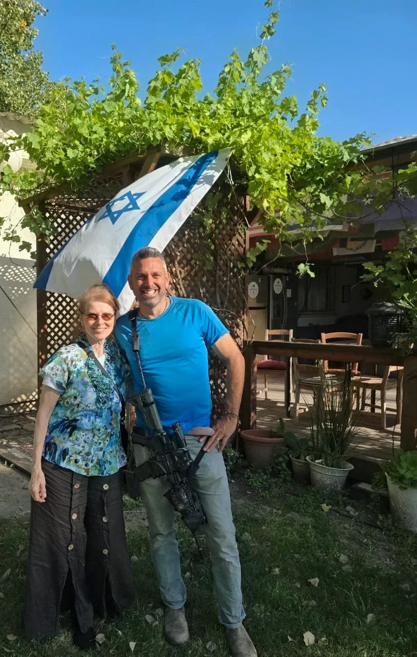 Margaret standing with a friend beneath an Israeli flag