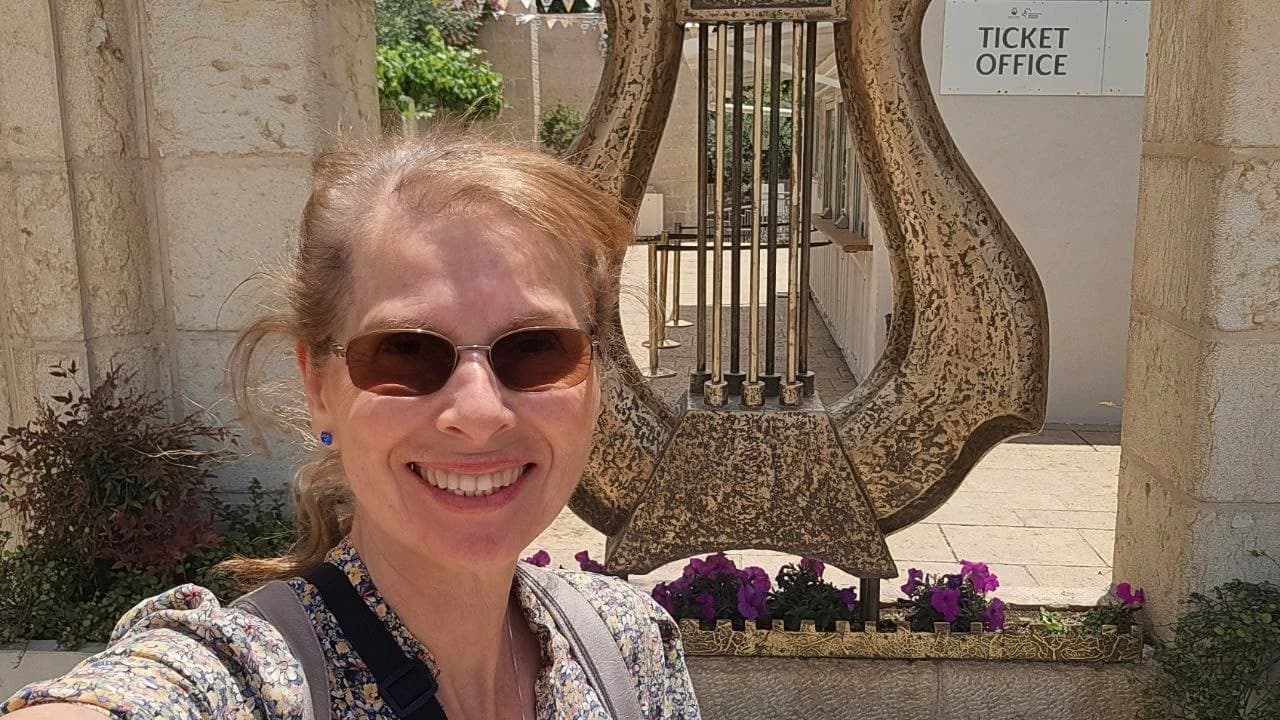 Margaret beside a large outdoor harp sculpture