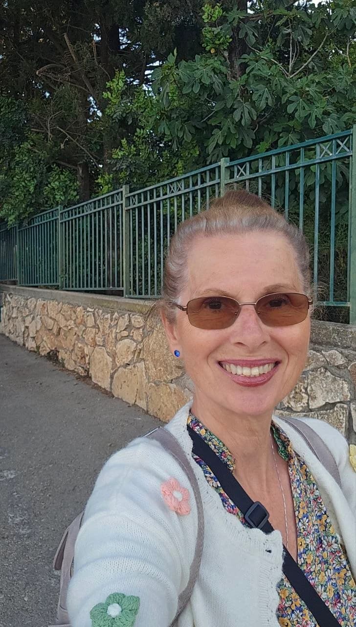Margaret smiling along a tree-lined stone walkway