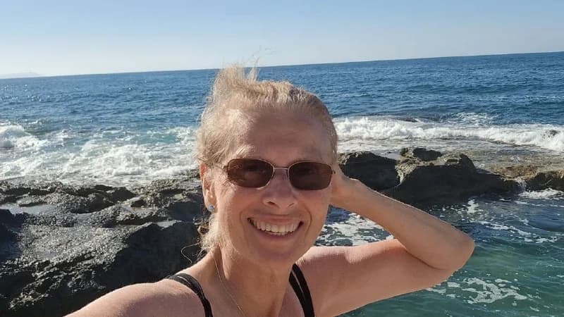 Margaret smiling beside the rocky coast