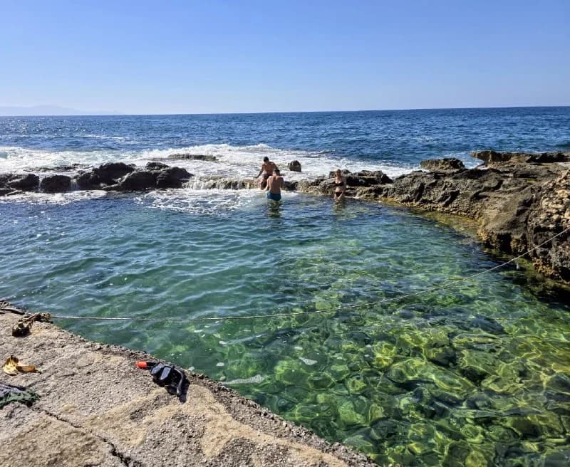 A swimmer in a clear natural rock pool by the sea
