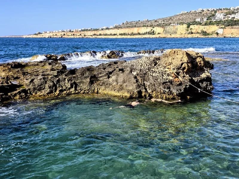 A calm blue rock pool beside the open sea