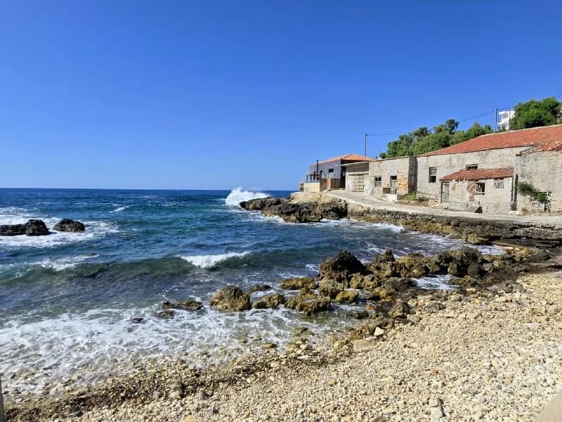 Stone houses lining a rocky blue shoreline