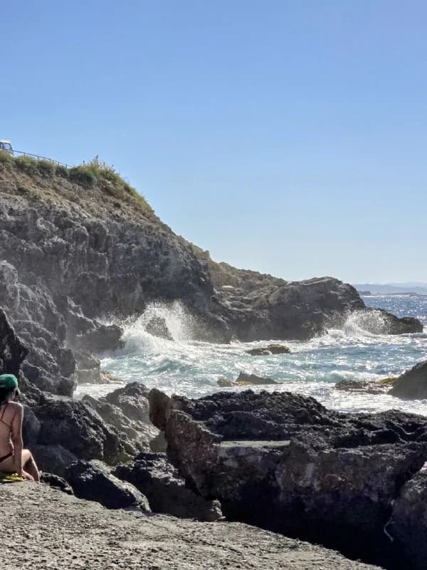 Sea waves breaking against steep dark cliffs
